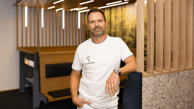 Dr. Thomas Katzhammer lehnt an einer Wand im Wartebereich