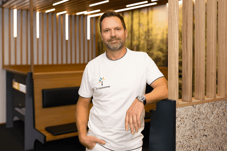 Dr. Thomas Katzhammer lehnt an einer Wand im Wartebereich